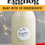 Pinterest photo of Spiked Eggnog with a glass bottle of eggnog on a red cloth with sparkling lights in the background. Says 'Spiked Eggnog, make with 10 ingredients, so easy, shakedrinkrepeat.com'