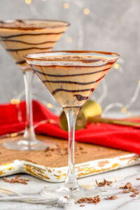 Front facing photo of Chocolate Martini in a chocolate drizzled martini glass with another martini behind it.