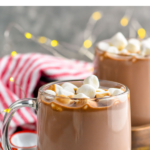pinterest graphic for crockpot hot chocolate. Text says "the best crockpot hot chocolate shakedrinkrepeat.com" Image shows two mugs of crockpot hot chocolate topped with marshmallows.