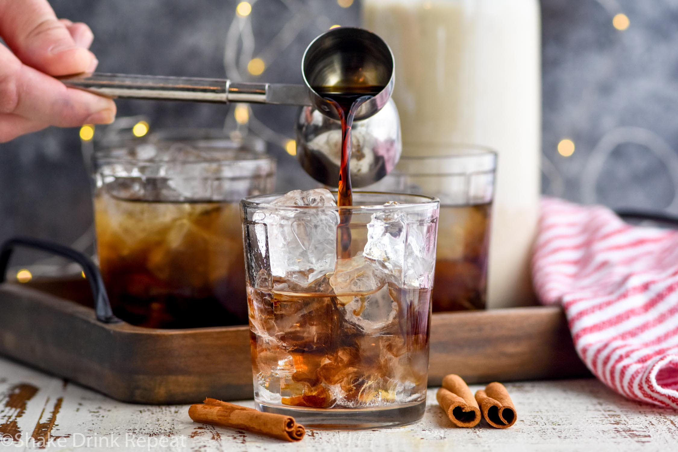 Horizontal image of coffee liqueur being poured into an Eggnog White Russian