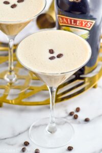 Overhead photo of two Baileys Espresso Martinis garnished with three coffee beans. Bottle of Baileys in the background.