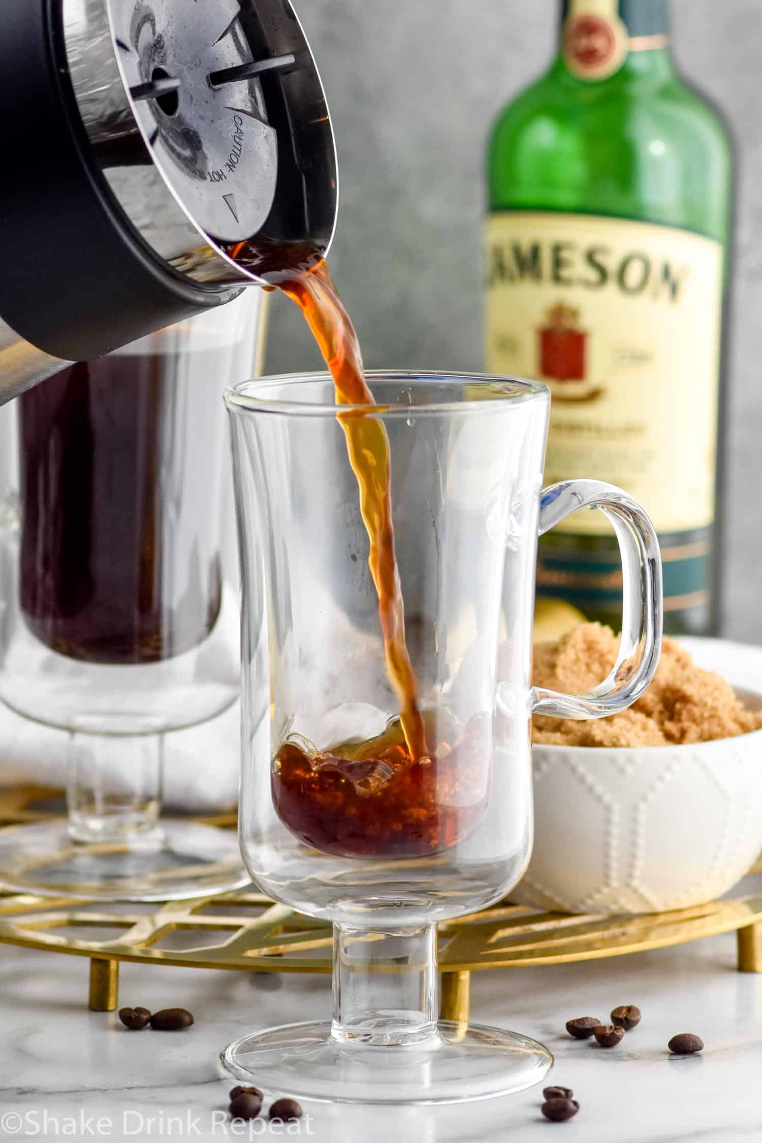 Photo of coffee being poured into a mug for Irish Coffee recipe. Bowl of brown sugar and a bottle of Jameson Irish Whiskey are in the background.
