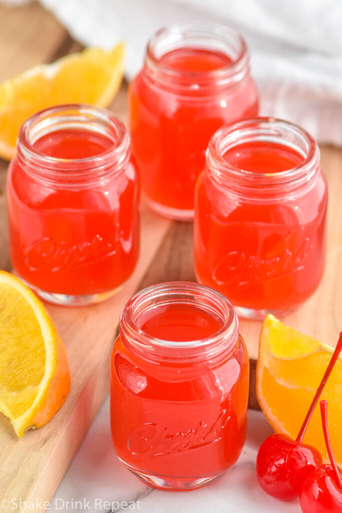 Overhead photo of Alabama Slammer Shots. Cherries and orange slices beside shot glasses.