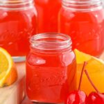 Close up photo of Alabama Slammer Shots. Orange slices and cherries sit beside shots.