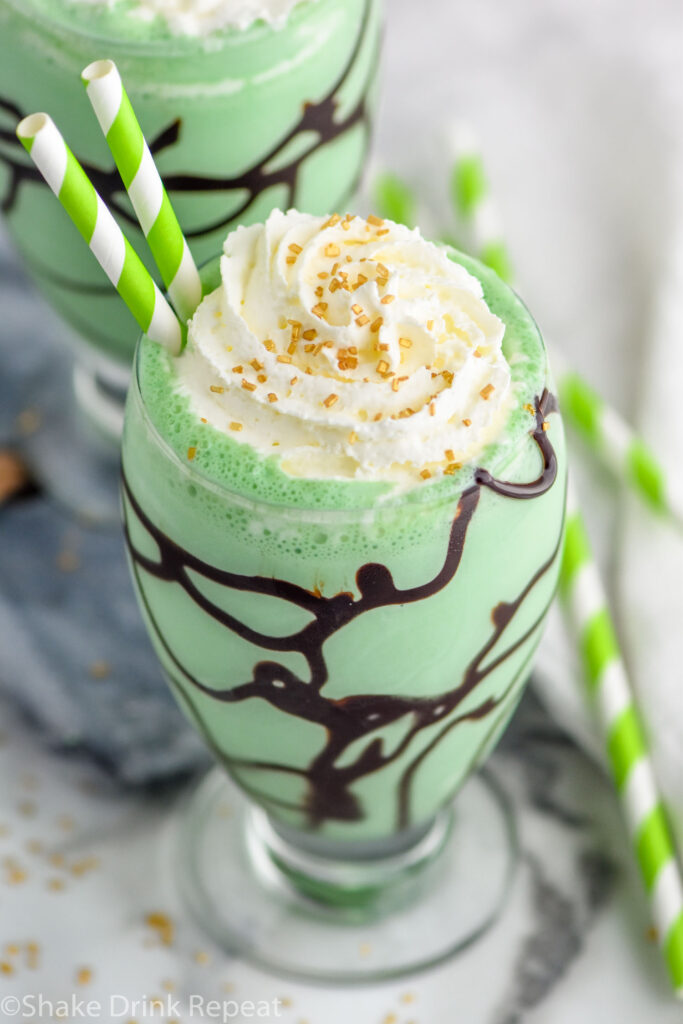 Overhead photo of St. Patrick's Day Mudslide garnished with shipped cream and gold sprinkles. Straws for drinking.