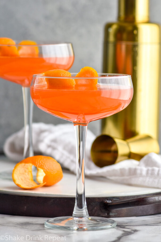 Close up photo of two Paper Plane cocktails with a shaker bottle in the background.