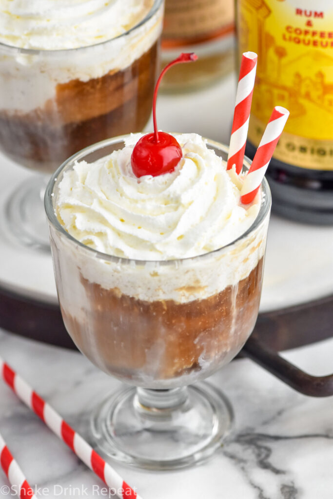 Overhead photo of White Russian Float garnished with whipped cream and a cherry, with straws for drinking.