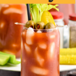 Pinterest graphic for Bloody Mary recipe. Text says, "Vodka Bloody Mary shakedrinkrepeat.com." Photo of Bloody Mary garnished with olives, celery, and a pickle. Extra olives, celery, and pickles on counter beside Bloody Mary glass.