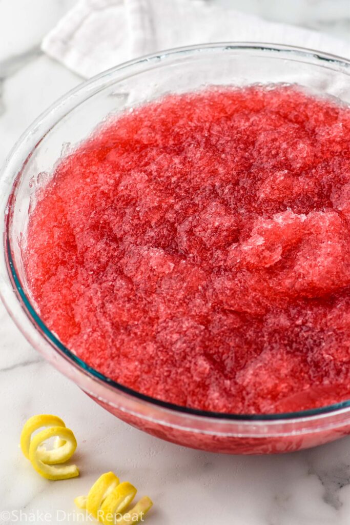 Photo of bowl of Frozen Cosmos recipe. Lemon twists beside bowl for garnish.