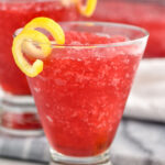 Side view of Frozen Cosmo garnished with lemon twist.