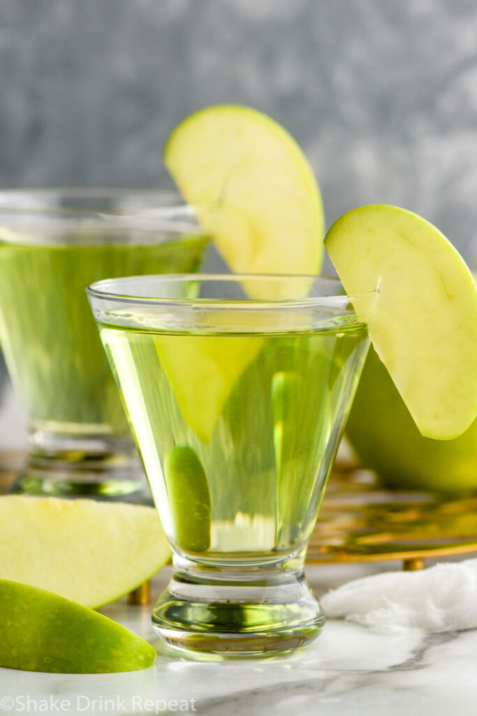 Two glasses of appletini cocktails garnished with an apple slice