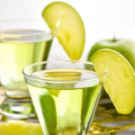 Pinterest graphic for Appletini. Text says "the best appletini shakedrinkrepeat.com" Image shows two glasses of appletini garnished with an apple slice.