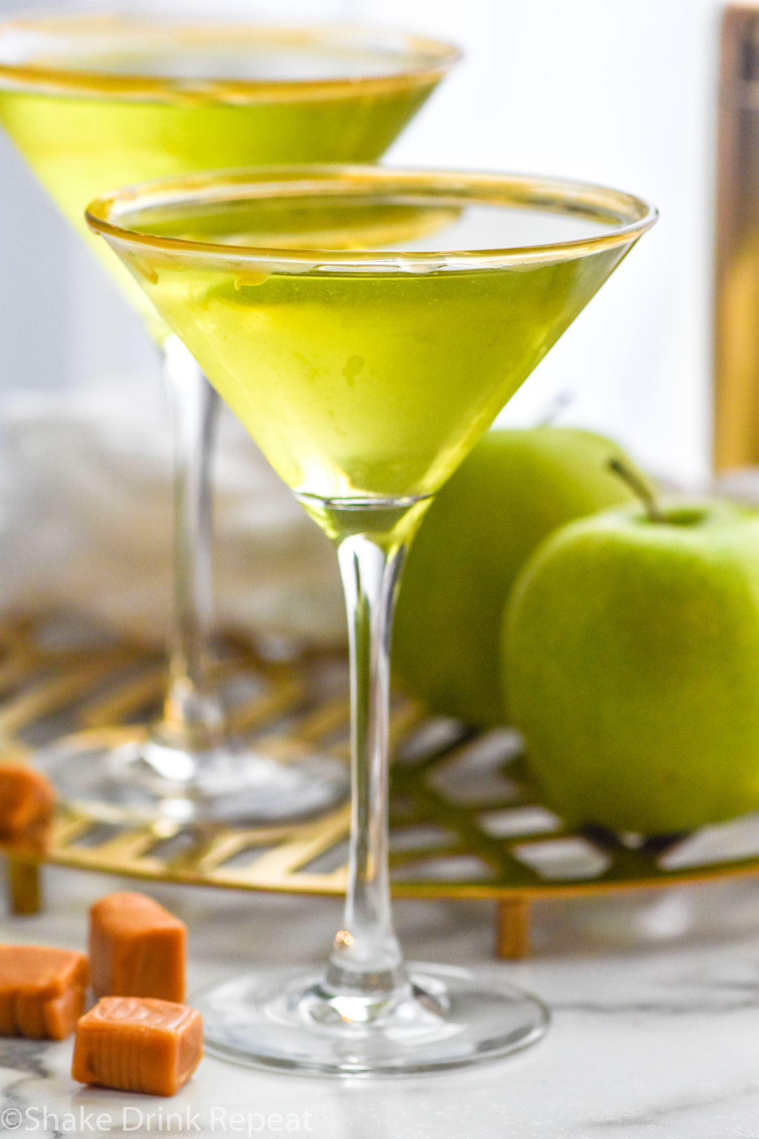 Side view of Caramel Apple Martini with apples and caramel beside