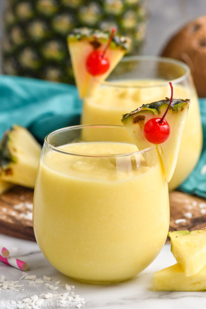 Side view of Non Alcoholic Pina Colada mocktails garnished with pineapple wedges and cherries.