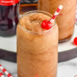 Frozen Jack and Coke with straw and cherry. Bottle of coca cola beside.