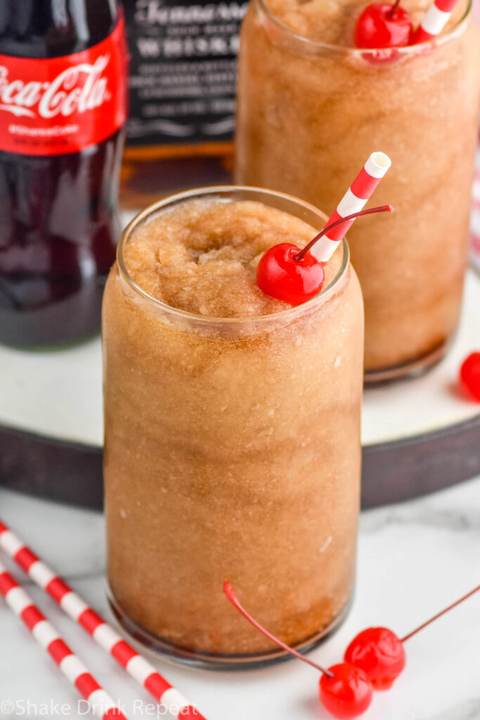 Frozen Jack and Coke with straw and cherry. Bottle of coca cola beside.