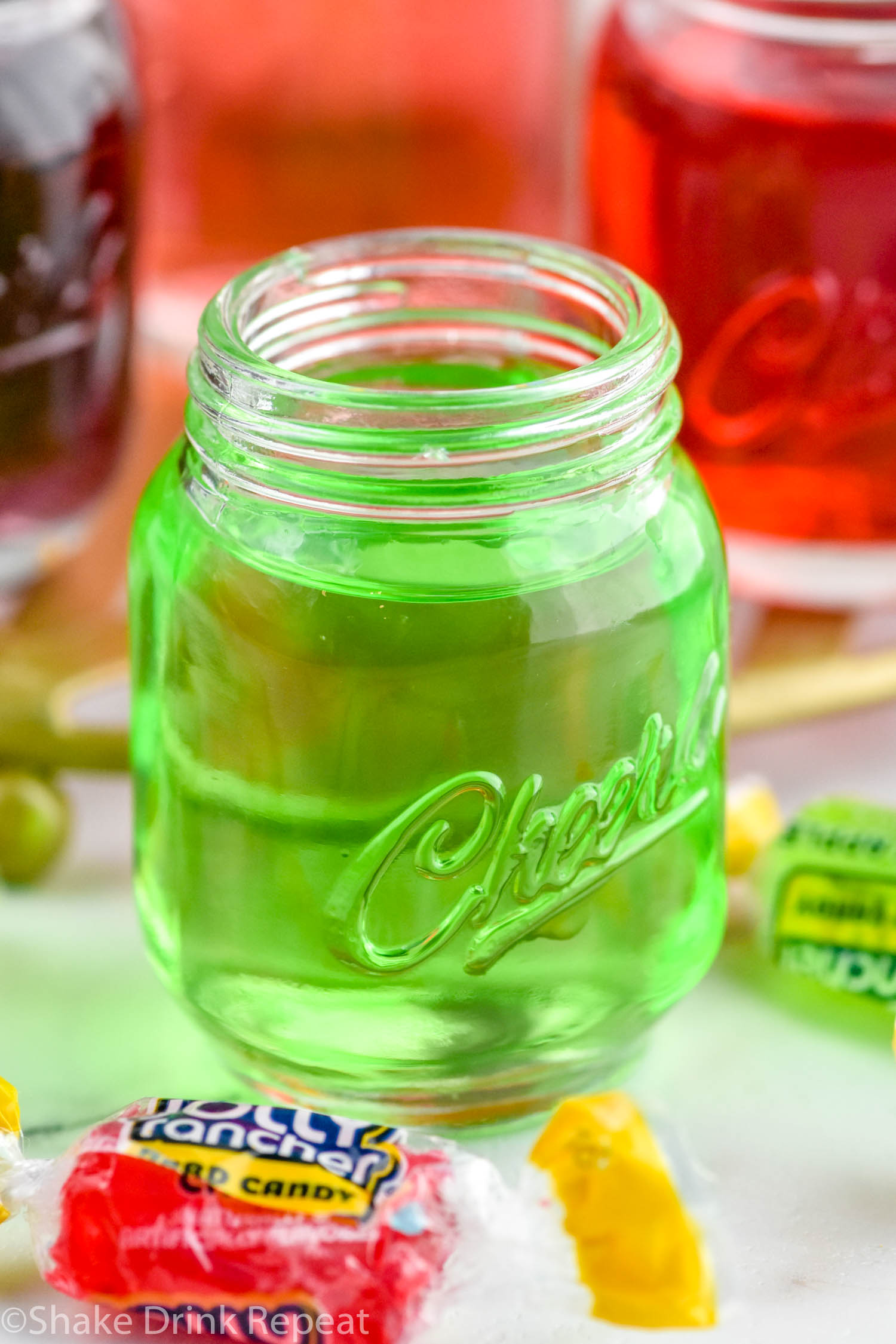 Photo of green Jolly Rancher shot with Jolly Rancher candies beside