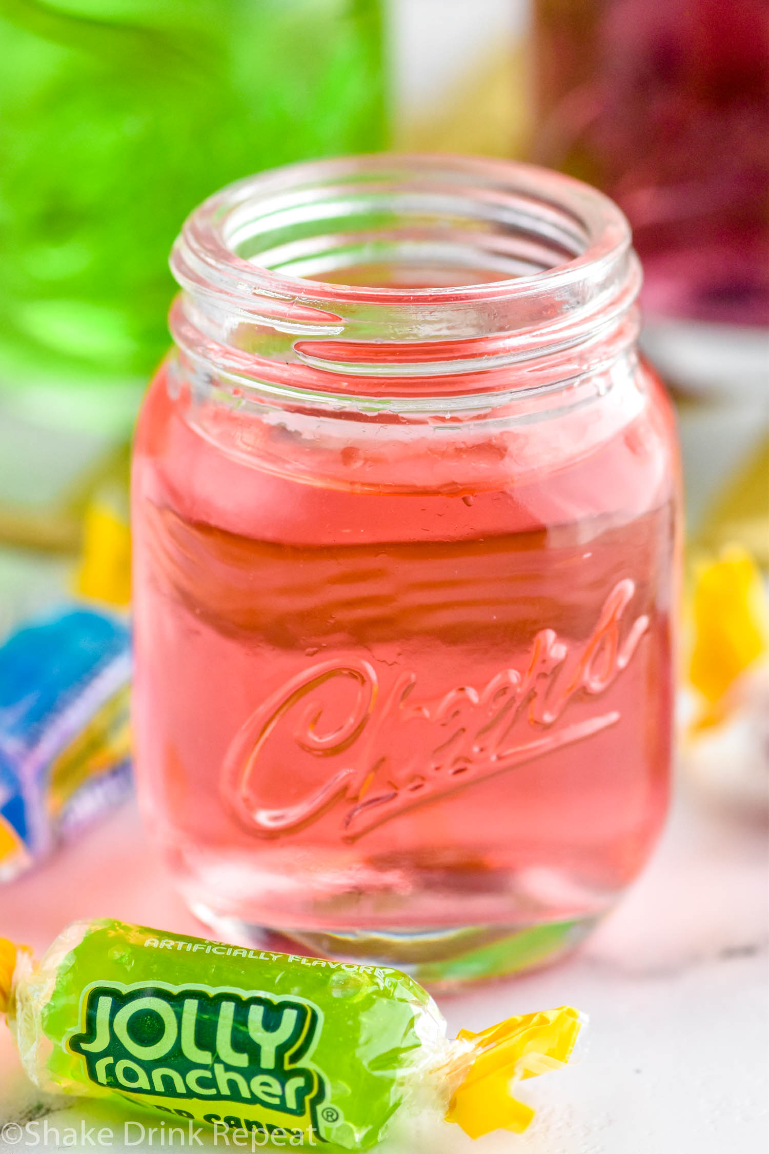 Photo of pink Jolly Rancher shot with Jolly Rancher candies beside