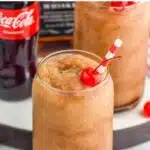 Pinterest graphic for Frozen Jack and Coke recipe. Text says, "the best Frozen Jack and Coke only uses 2 simple ingredients! shakedrinkrepeat.com." Image shows Frozen Jack and Coke with straw and cherry.