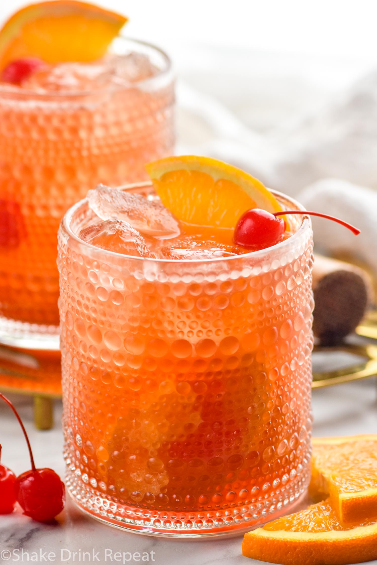 Cherry Old Fashioned garnished with orange slices and cherries