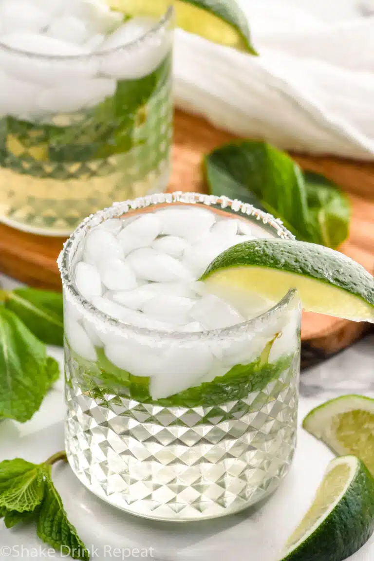 two glasses of Mojito Margarita with fresh mint leaves and lime wedges surrounding